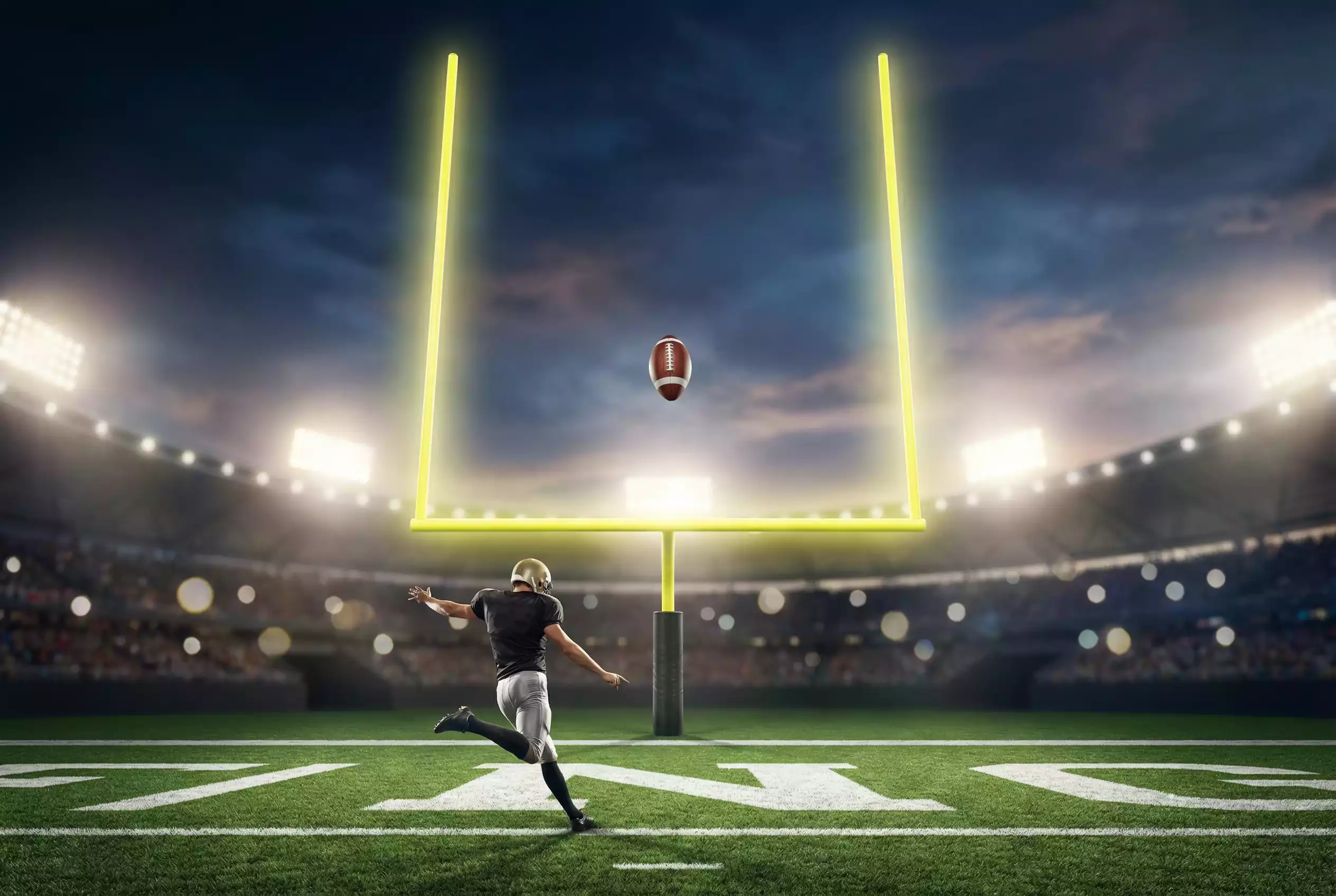 American-Football-Spieler beim Field-Goal-Kick zwischen den Torpfosten