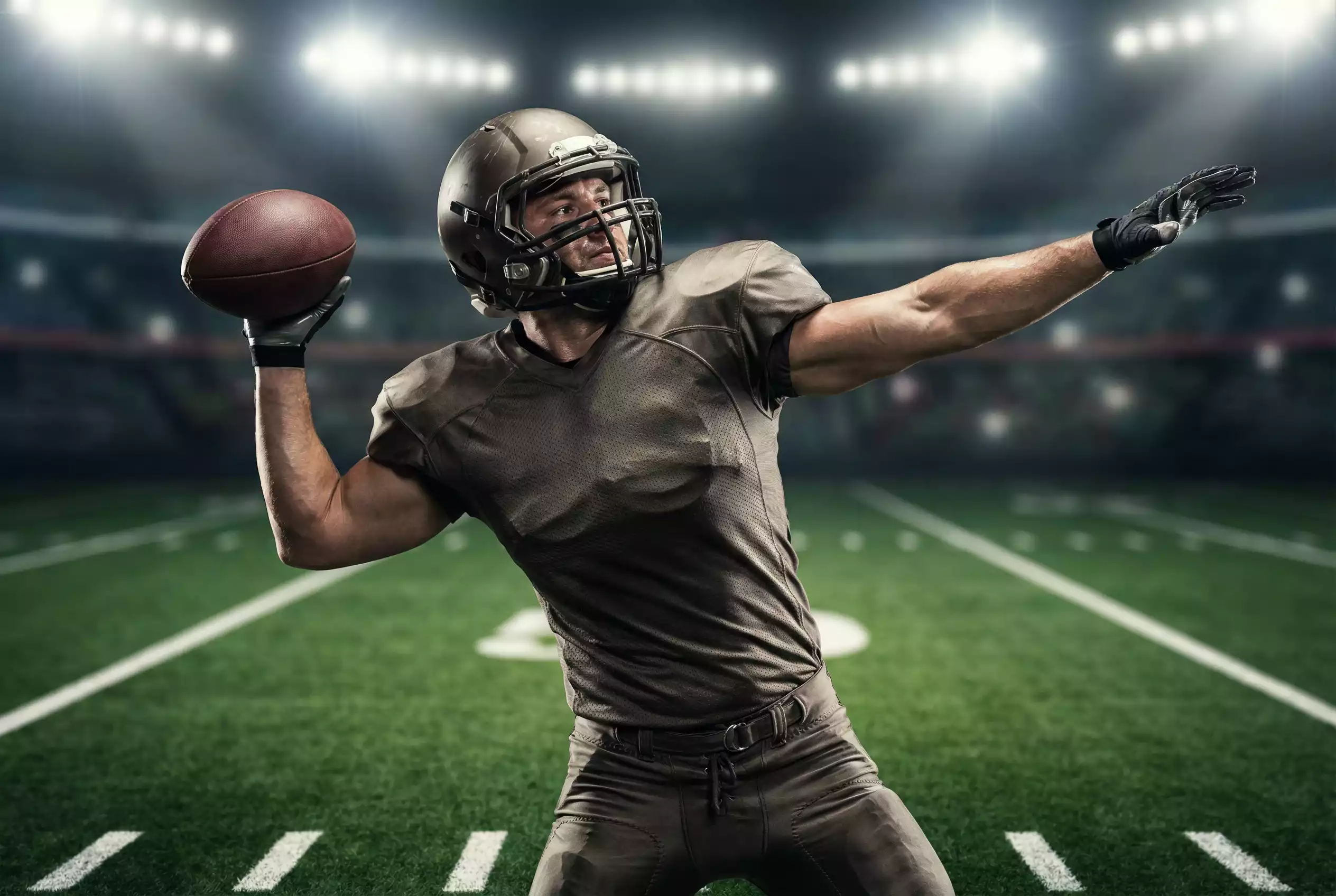 NFL-Quarterback wirft einen Pass unter Stadionflutlicht