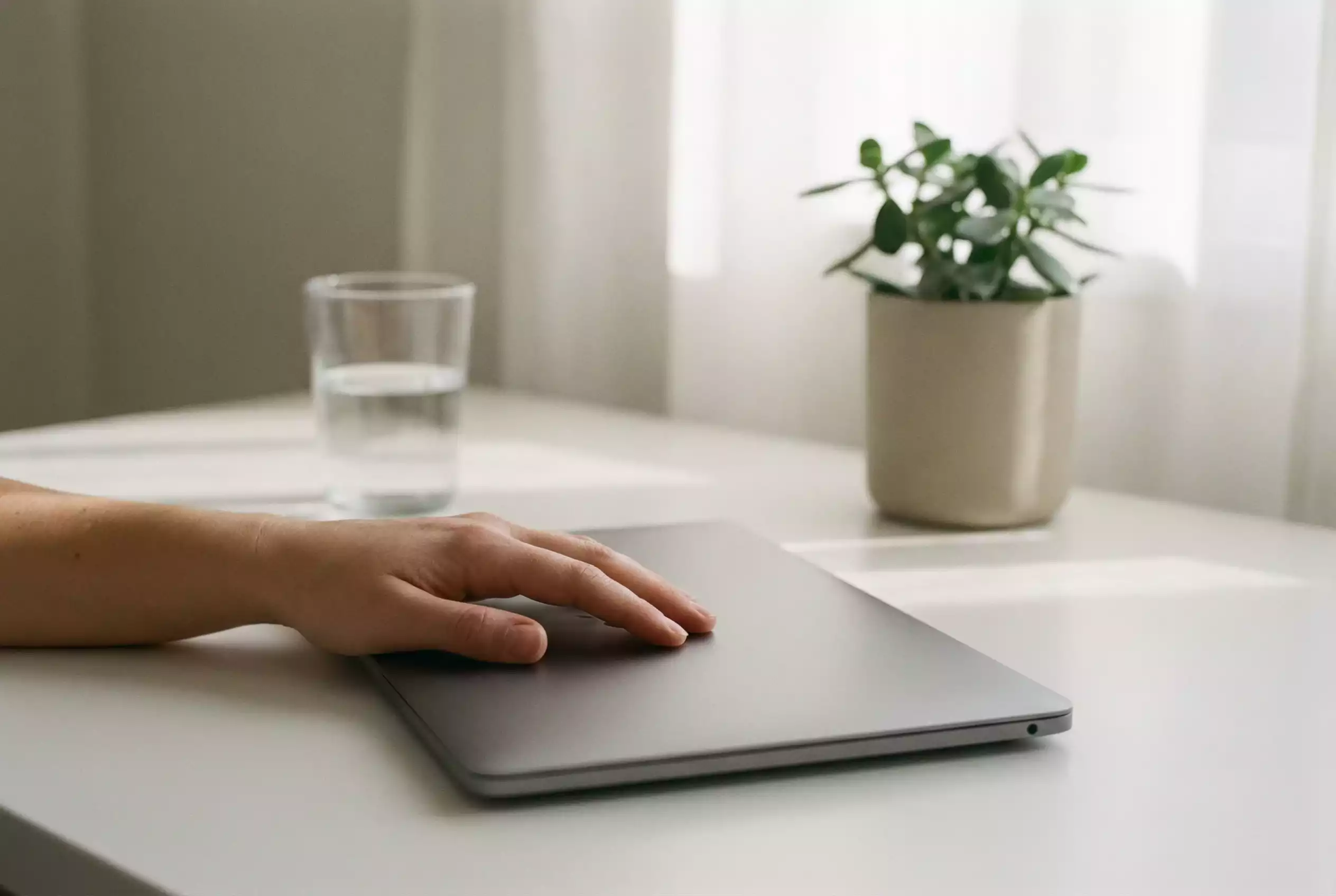 Ruhige Hand auf einem geschlossenen Laptop symbolisiert Selbstkontrolle